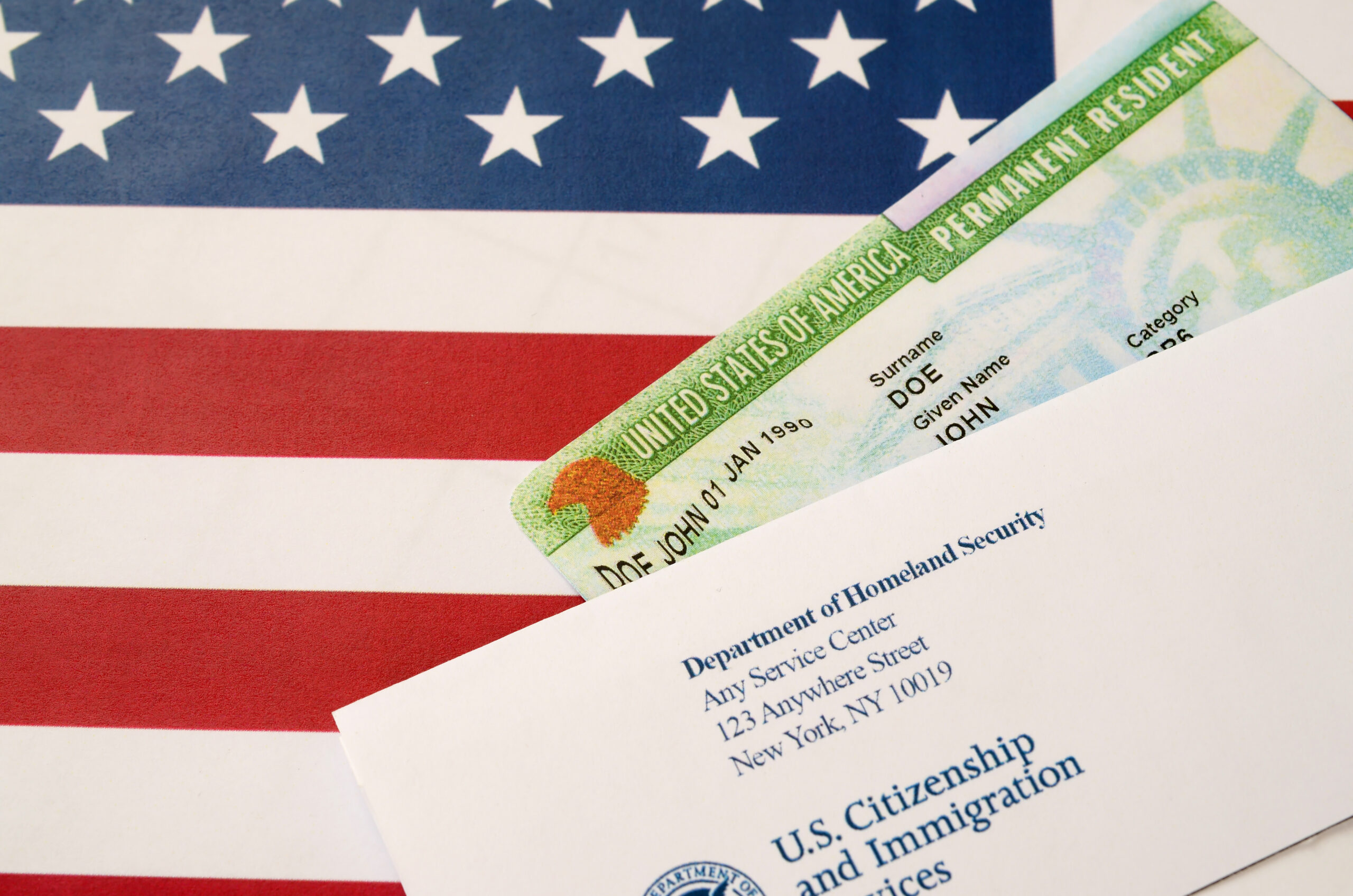 United States Permanent resident green card from dv-lottery lies on United States flag with envelope from Department of Homeland Security United States Permanent resident green card from dv-lottery lies on United States flag with envelope from Department of Homeland Security close up